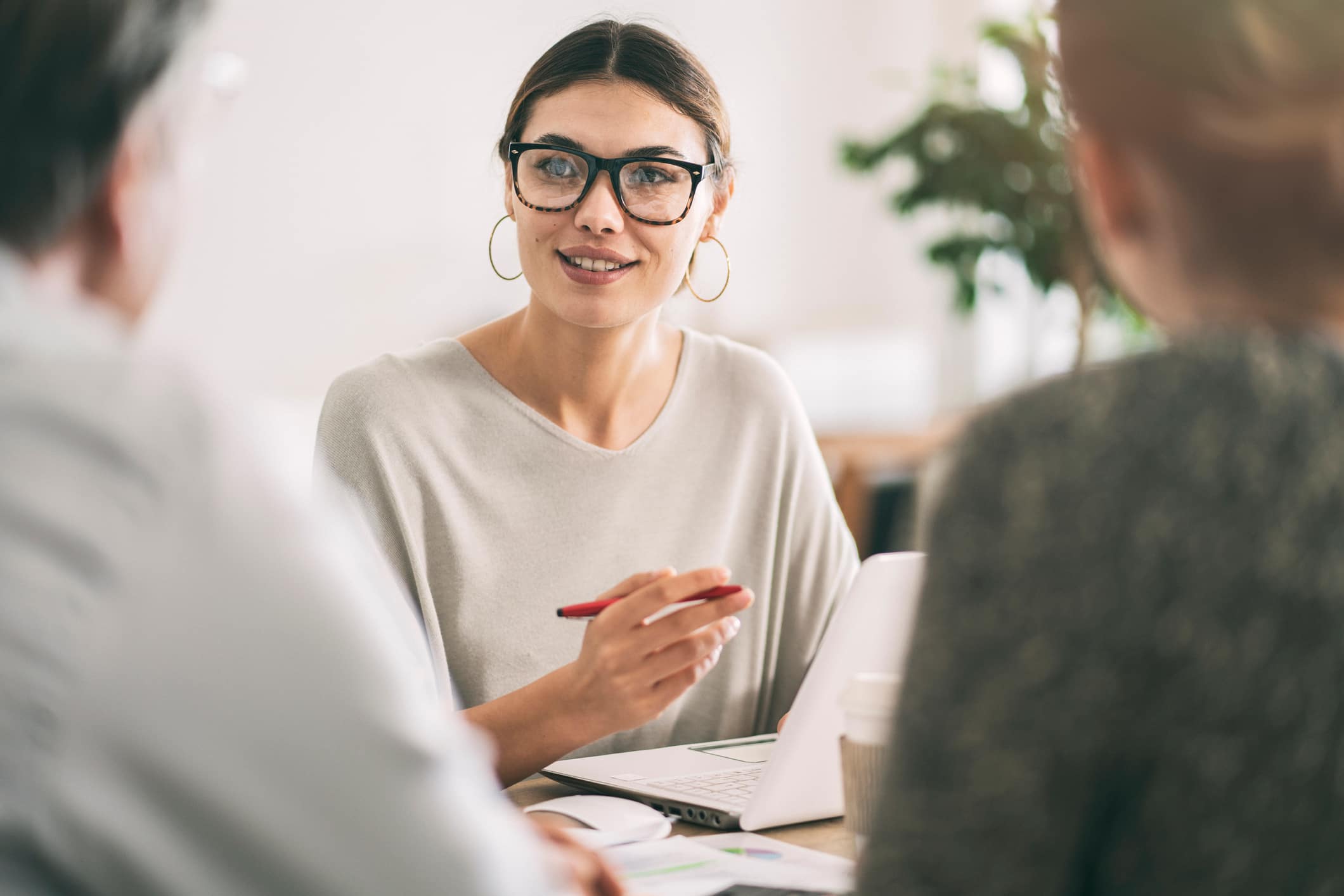 A female reinsurance broker talks to two clients at a desk