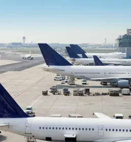 Planes lines up in an airport are loaded with cargo
